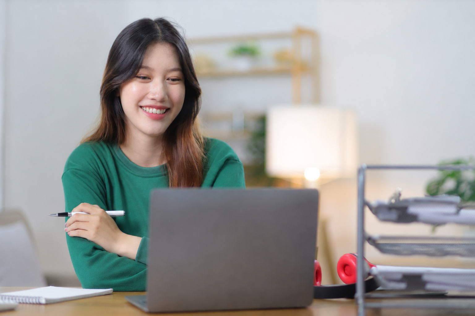 woman wearing green looking at a laptop