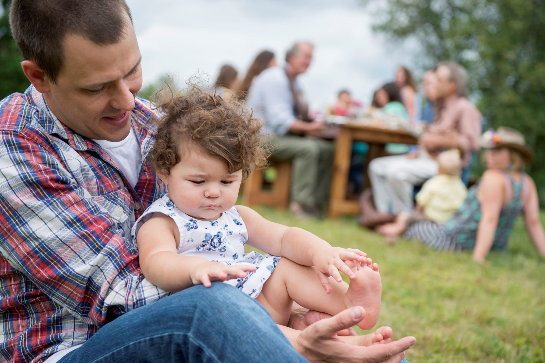 father with daughter sitting in front of family picnic