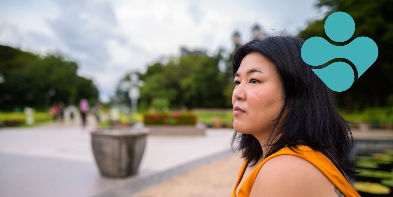 woman sat in park with blue icon in top right corner